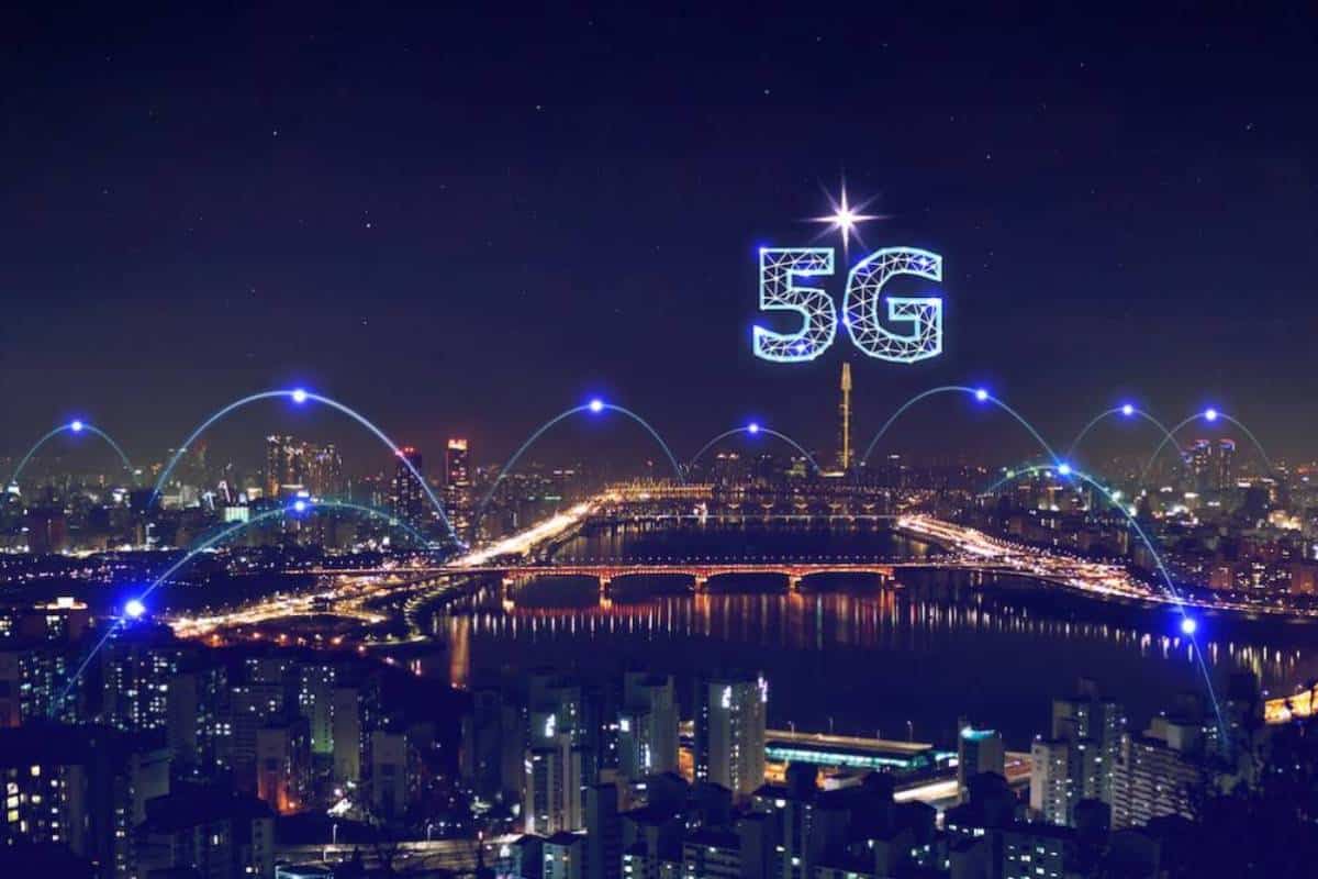 A nighttime cityscape showcases glowing 5G above a river
