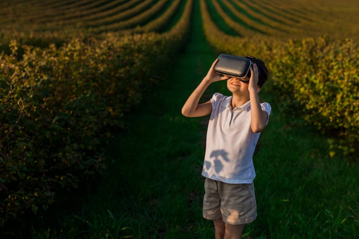 Young boy using virtual reality headset in a lush green orchard at sunset.