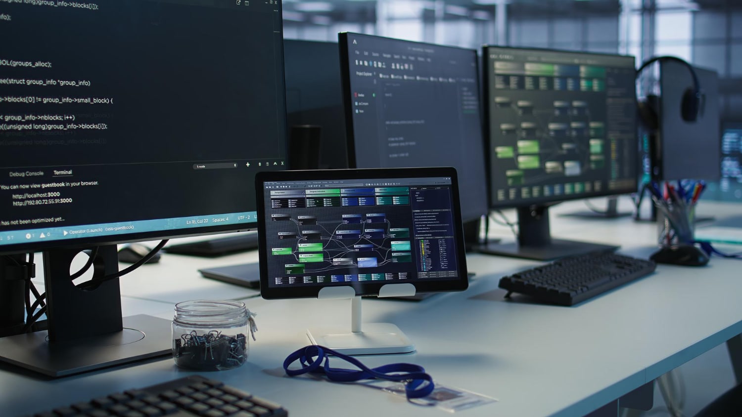 A modern workspace featuring multiple computer monitors displaying code and data flow diagrams