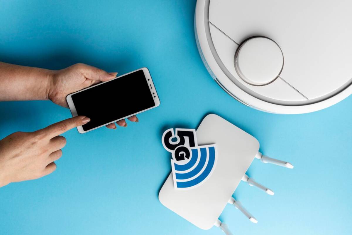 A person using a smartphone to control a robotic vacuum cleaner on a blue background.